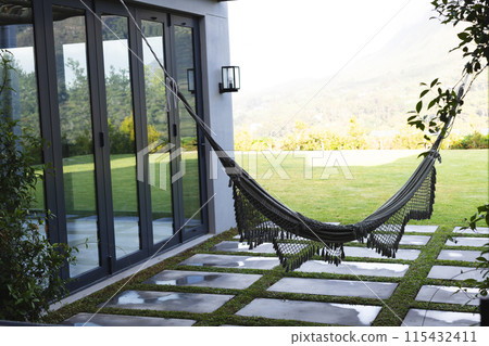 A black hammock hangs invitingly in a modern home's backyard with copy space A black hammock hangs invitingly in a modern home's backyard with copy space 115432411
