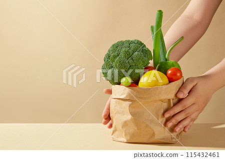 Front view photo background on yellow background. On the right side of table containing a paper bag of variety fresh vegetable, having a hand is keeping it. Vacant space for product displaying Front view photo background on yellow background. On the right side of table containing a paper bag of variety fresh vegetable, having a hand is keeping it. Vacant space for product displaying 115432461