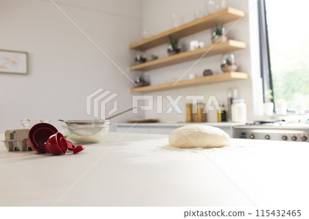 A kitchen counter is dusted with flour, featuring dough and a red measuring cup with copy space A kitchen counter is dusted with flour, featuring dough and a red measuring cup with copy space 115432465
