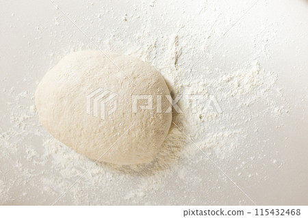 A ball of dough sits amidst a dusting of flour on a surface with copy space 115432468