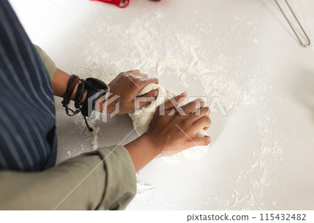 Hands knead dough on a flour-dusted surface with copy space, revealing a baking process 115432482