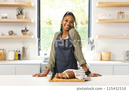 A young African American woman stands with a confident smile in a bright kitchen A young African American woman stands with a confident smile in a bright kitchen 115432518