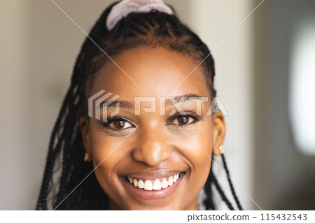 A young African American woman smiles brightly, her braided hair adorned with a headband A young African American woman smiles brightly, her braided hair adorned with a headband 115432543