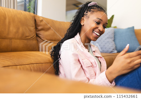 A young African American woman smiles while looking at her phone, with copy space A young African American woman smiles while looking at her phone, with copy space 115432661