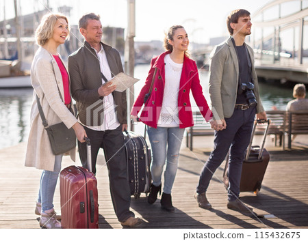Tourists with suitcases and camera walk along the pavement in port of European city 115432675