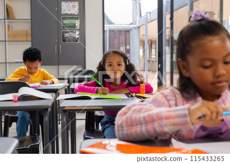 African American boy and two biracial girls focused on their schoolwork in a school classroom African American boy and two biracial girls focused on their schoolwork in a school classroom 115433265