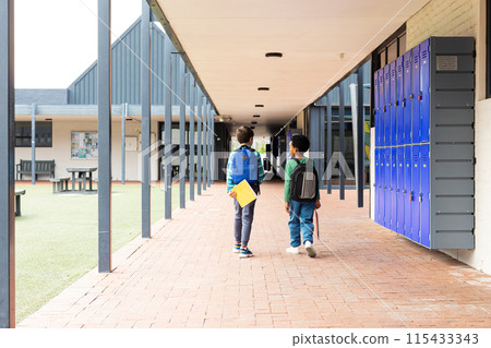 Biracial boy and African American boy walk down a school corridor 115433343