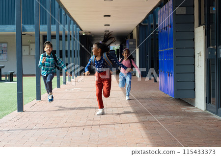 Biracial boy and girl are running joyfully through a school corridor Biracial boy and girl are running joyfully through a school corridor 115433373