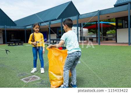 Biracial girl and boy are picking up trash, the girl in a yellow top and the boy in a white tee 115433422