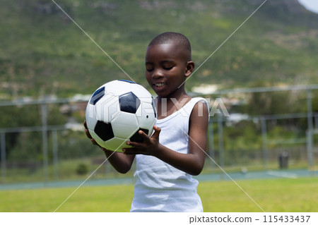 African American boy holds a soccer ball outdoors in school 115433437