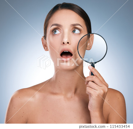 Woman, shock and magnify glass for skincare or beauty, botox and anti aging on blue background. Cosmetology, retinol and spot control for treatment, pamper and dermatology for female person in studio 115433454