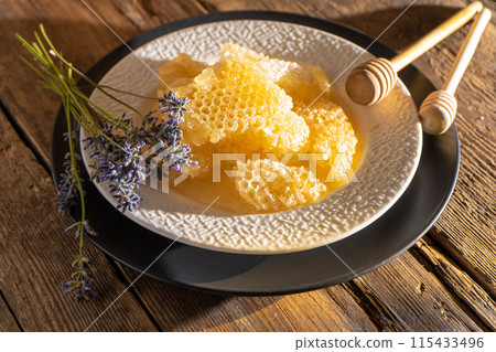 Honey and honeycombs on a white plate. Sweet food in a bowl on the table. A product of beekeeping Honey and honeycombs on a white plate. Sweet food in a bowl on the table. A product of beekeeping 115433496