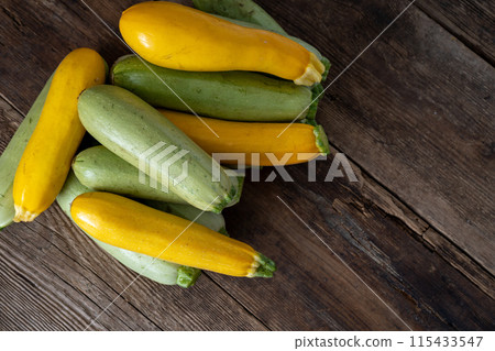 Multi-colored zucchini yellow, green, white, orange on the wooden table close-up. Food background. Fresh harvested courgette, cropped summer squash. Picked green courgettes. Still life in kitchen Multi-colored zucchini yellow, green, white, orange on the wooden table close-up. Food background. Fresh harvested courgette, cropped summer squash. Picked green courgettes. Still life in kitchen 115433547