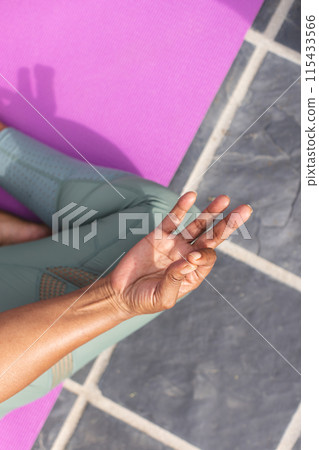 Senior African American woman practices yoga, showing a mudra with her hand, with copy space 115433566