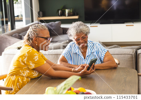 Senior African American woman and biracial woman share a moment looking at a smartphone at home 115433701