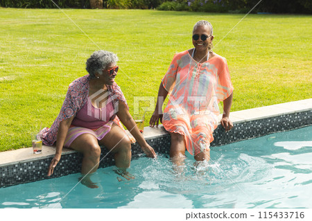 Senior African American woman and senior biracial woman enjoy a poolside chat Senior African American woman and senior biracial woman enjoy a poolside chat 115433716