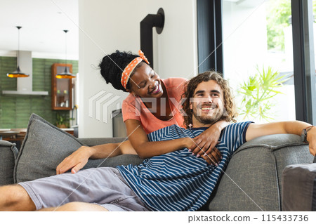 Diverse couple enjoys a relaxed moment on a gray sofa 115433736