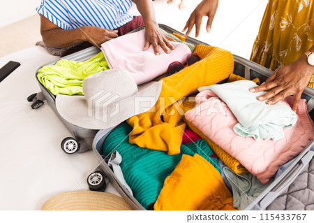 Senior African American woman and senior biracial woman pack a suitcase Senior African American woman and senior biracial woman pack a suitcase 115433767
