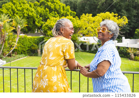 Senior African American woman and senior biracial woman share a joyful moment outdoors 115433826