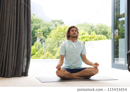 Young Caucasian man meditates in a serene indoor setting, eyes closed in concentration Young Caucasian man meditates in a serene indoor setting, eyes closed in concentration 115433854