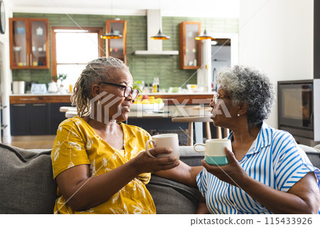 Senior African American woman and senior biracial woman share a conversation over coffee at home 115433926