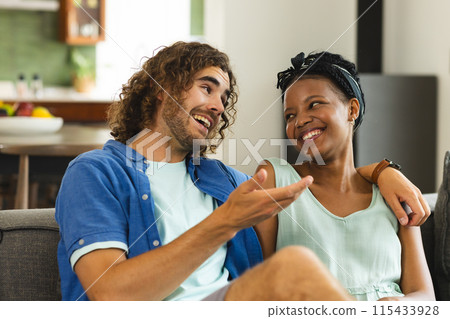 Diverse couple, young Caucasian man and African American woman share a joyful moment on a couch 115433928