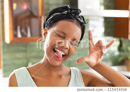 Young African American woman enjoys a playful moment, making a fun gesture with her hand 115433936
