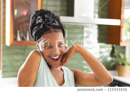 Young African American woman smiles with joy, her hands framing her face 115433938
