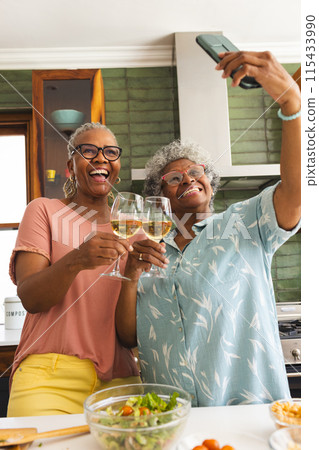 Senior African American woman and senior biracial woman take a selfie with wine glasses Senior African American woman and senior biracial woman take a selfie with wine glasses 115433990