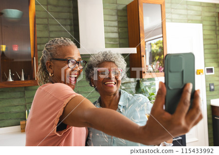 Senior African American woman and senior biracial woman are taking a selfie with a phone Senior African American woman and senior biracial woman are taking a selfie with a phone 115433992