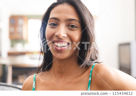 Young biracial woman with a cheerful smile, wearing a green top 115434612