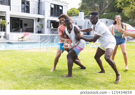 Diverse group of friends playfully tussle over a ball in a sunny backyard with copy space Diverse group of friends playfully tussle over a ball in a sunny backyard with copy space 115434659