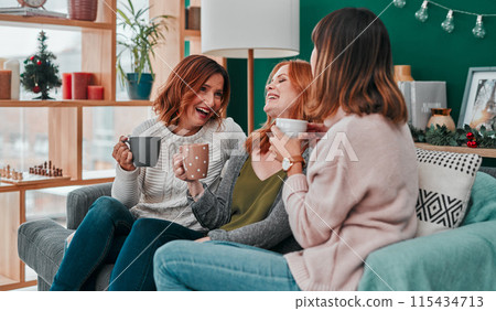 Christmas, group and friends with coffee, laughing or happy in vacation of festive season and funny. Home, lounge or people with hot chocolate, warm or smile of girls, together and excited for winter 115434713