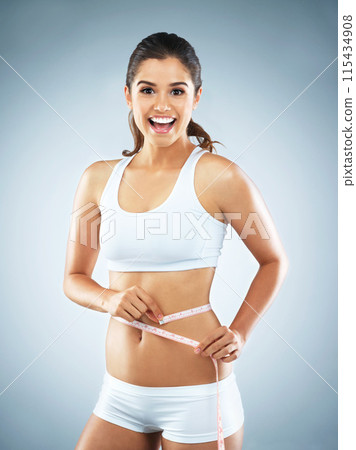 Stomach, portrait or happy woman with tape measure for wellness, body progress or workout in studio. Girl, smile or proud athlete with exercise, fitness or training to lose weight on blue background Stomach, portrait or happy woman with tape measure for wellness, body progress or workout in studio. Girl, smile or proud athlete with exercise, fitness or training to lose weight on blue background 115434908