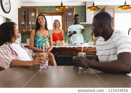 Diverse group of friends enjoys a casual gathering in a modern kitchen Diverse group of friends enjoys a casual gathering in a modern kitchen 115434958