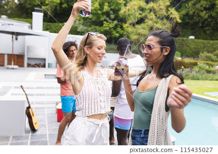 A diverse group of friends enjoys a poolside gathering during the day A diverse group of friends enjoys a poolside gathering during the day 115435027