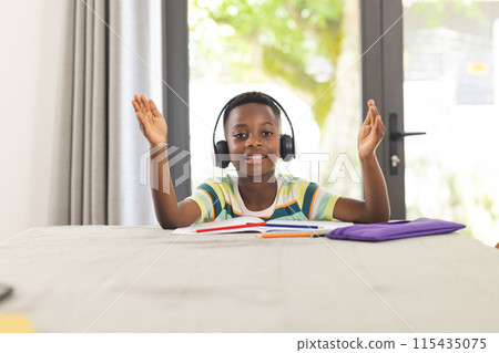 African American boy with headphones gestures during an online class African American boy with headphones gestures during an online class 115435075