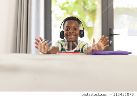 African American boy with headphones smiles at the camera, hands outstretched, with copy space African American boy with headphones smiles at the camera, hands outstretched, with copy space 115435076
