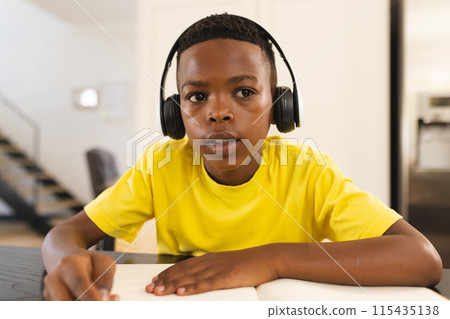 A young African American boy is focused on his homework during an online school lesson on video call 115435138