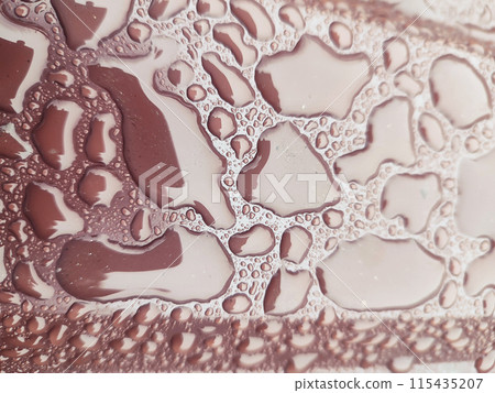 Raindrops under plastic wrap on brown surface 115435207