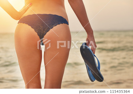 Legs, butt and woman with bikini on beach for summer vacation, flip flops and sunset walk for peace. Ocean, travel and buttocks of girl for island holiday with health and relax with tropical paradise 115435364