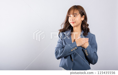 A happy business woman in casual attire holds her hands close to her chest, meditating and smiling. Studio shot isolated on a white background, portraying the concepts of belief, faith, and gratitude A happy business woman in casual attire holds her hands close to her chest, meditating and smiling. Studio shot isolated on a white background, portraying the concepts of belief, faith, and gratitude 115435556