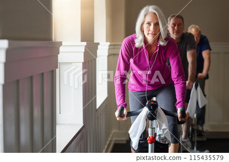 Gym, portrait or mature woman on bike machine in workout or training for endurance, health or wellness. Podcast, earphones or female sports person on cycling exercise for fitness, challenge or music Gym, portrait or mature woman on bike machine in workout or training for endurance, health or wellness. Podcast, earphones or female sports person on cycling exercise for fitness, challenge or music 115435579
