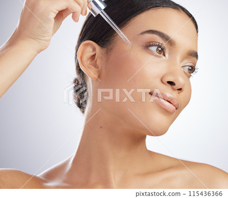 Skincare, face and girl with essential oil in studio for wellness, dermatology and hyaluronic acid application on grey background. Vitamin C, beauty and model with face serum, facial or retinol drip 115436366