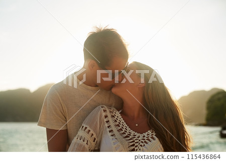 Couple, people and kiss on beach holiday, happy and love on travel adventure together for relationship bonding. Vacation, affection and trust outdoor for romance, summer ocean and nature for dating 115436864