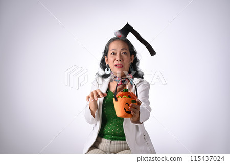 Senior woman holding halloween pumpkin baskets isolated white background 115437024