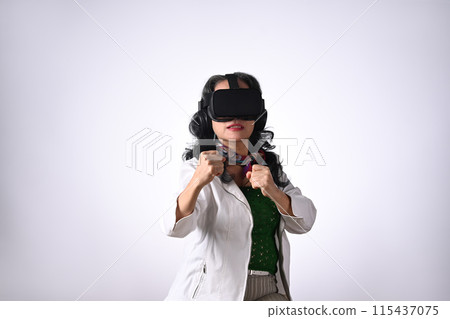 Senior woman in boxing stance, playing action simulator game in VR headset Senior woman in boxing stance, playing action simulator game in VR headset 115437075