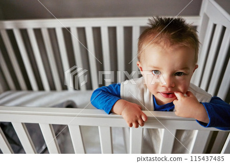 Portrait, happy and playful baby in crib on a blanket for child development, fun and entertainment. Happy, sweet and newborn for cheerful infant boy relaxing on a bed in his nursery or bedroom home Portrait, happy and playful baby in crib on a blanket for child development, fun and entertainment. Happy, sweet and newborn for cheerful infant boy relaxing on a bed in his nursery or bedroom home 115437485