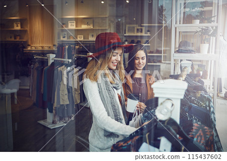 Shopping, store and girl friends by clothes in retail mall for discount, sale or promotion. Style, window and young women bonding and buying designer outfit on rack at luxury fashion boutique. Shopping, store and girl friends by clothes in retail mall for discount, sale or promotion. Style, window and young women bonding and buying designer outfit on rack at luxury fashion boutique. 115437602