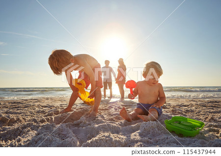 Beach, family and kids with sand castle in summer for holiday, travel or vacation together. Mother, father and children playing outdoor on tropical island coast for adventure, bonding or development 115437944